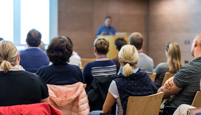 A speaker addresses a room full of people